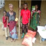 Four member of a family stand outside their home in Sierra Leone with a sack of rice and other food supplies they have just received.