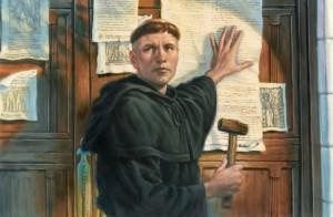 Martin Luther, dressed in black monk robes, stands in front of a wooden door with several pamphlets on it, as he nails his 95 theses to the door. He is holding a paper to the door with his left hand and holds a hammer in his right; he is looking away from the door, turned toward the viewer, looking at something to the left of the image.